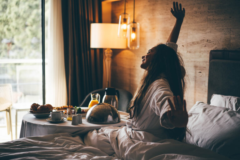 Woman eating breakfast in the hotel room. Room service breakfast in hotel room.